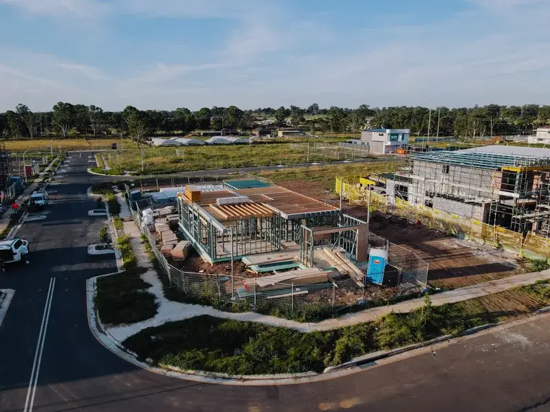 Aerial view of a single-storey house under construction, showing roof framing and the surrounding site