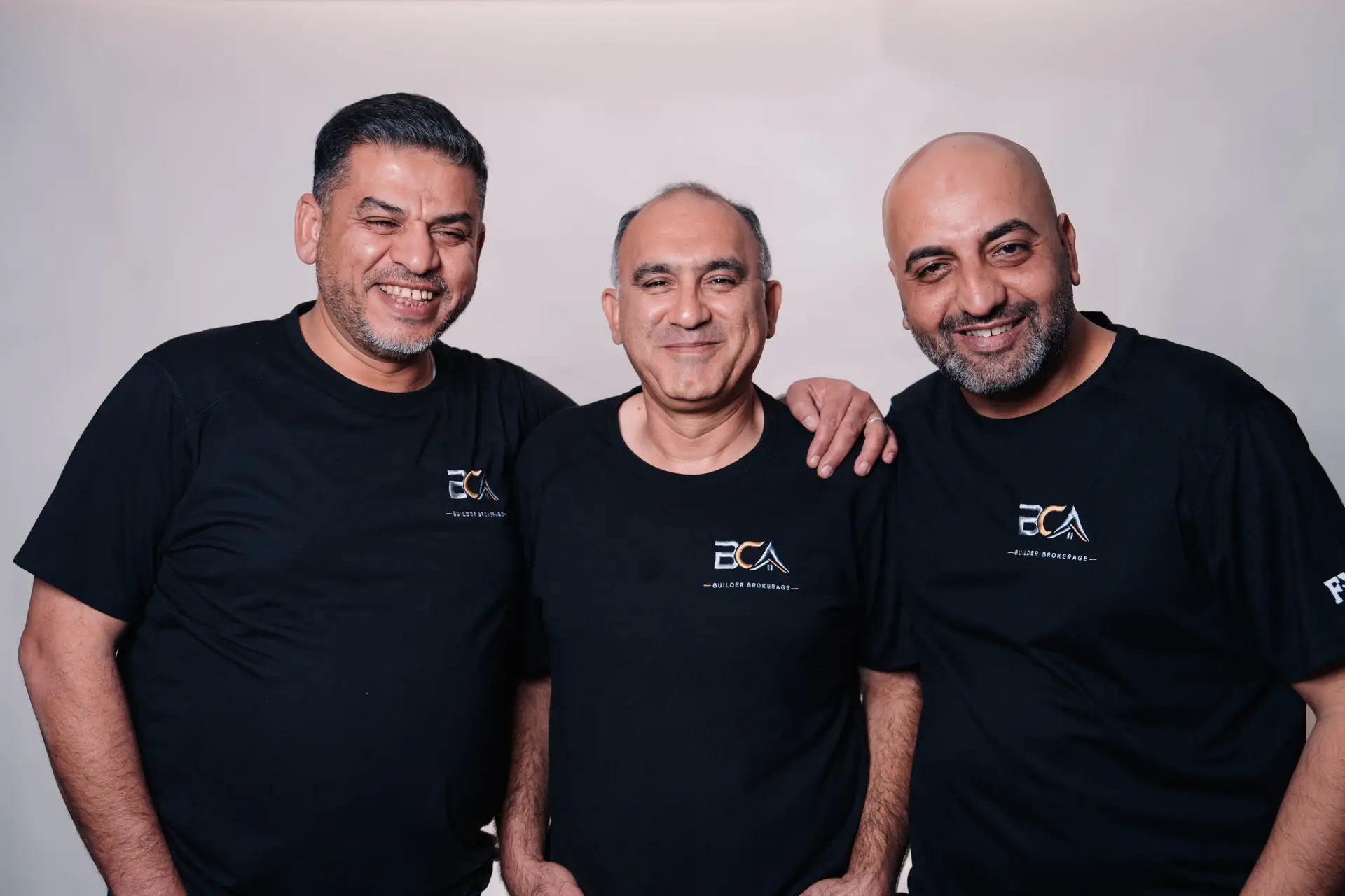 Three BCA team members smiling together in the studio